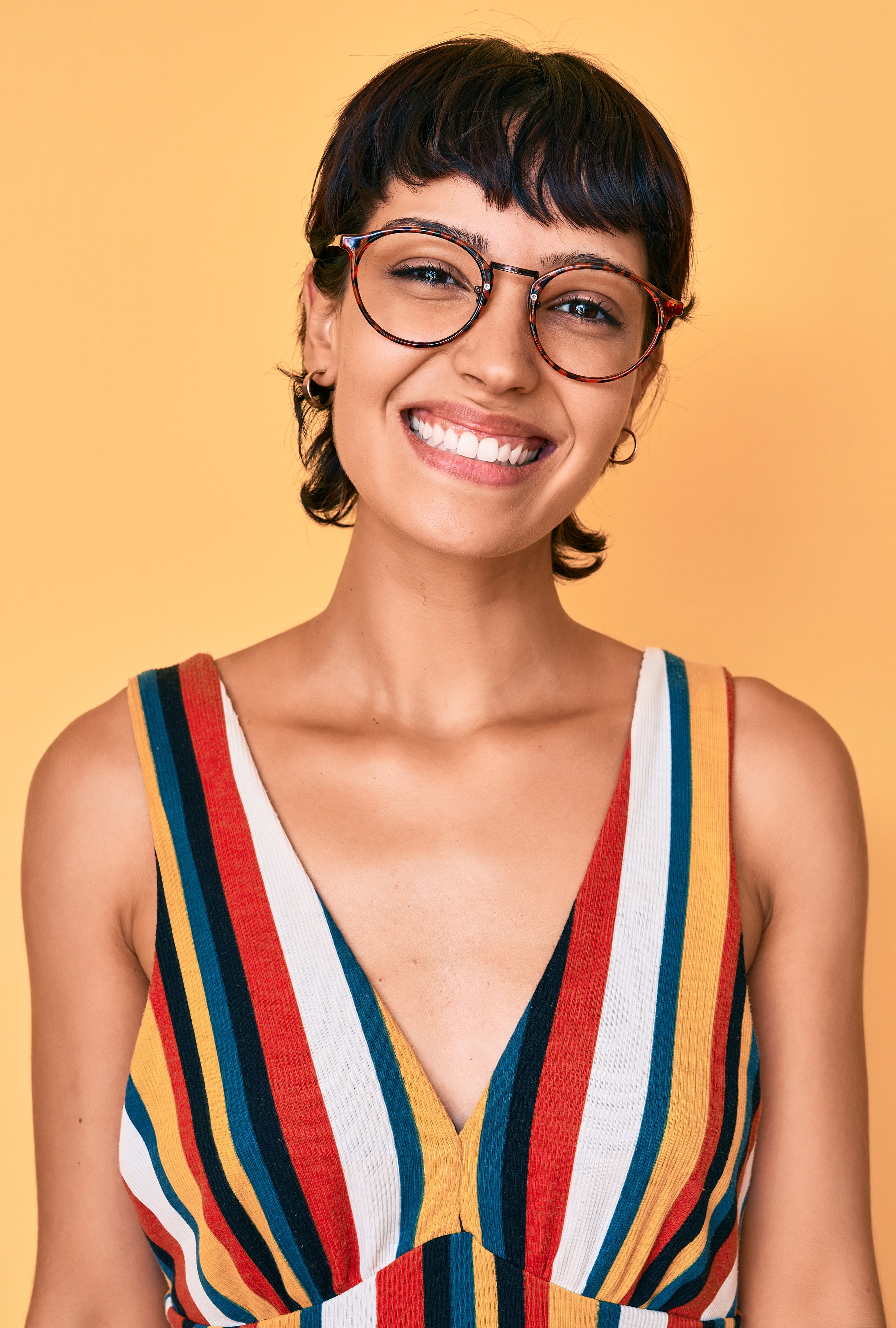 Das Bild zeigt eine junge Frau mit Brille, die ein gestreiftes Oberteil trägt.