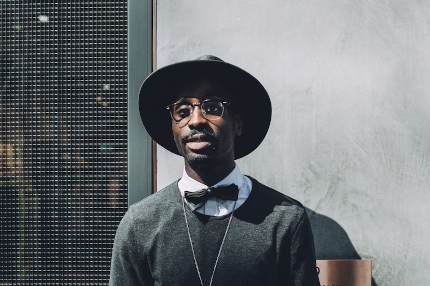 Das Bild zeigt einen Mann mit Hut, Brille und Fliege.